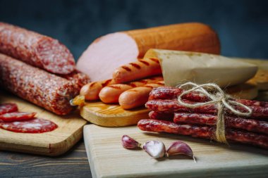 Tahta masada çeşitli et ve sosisler var. Gemide servis ediliyor, yakın plan. Üst görünüm.