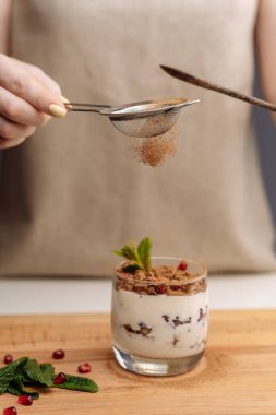Dişi eller iyi sindirim için çilekli yoğurt hazırlıyor, sindirim sistemi çalışıyor. Yaz meyveleri, fındık, meyve, süt ürünleri masada. Sağlıklı gıda konsepti.