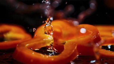 Dilimler halinde portakal dolma biber kahverengi ahşap tahtaya su damlalarıyla düşer.