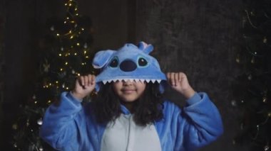 Komik Afrikalı küçük kız dans ediyor ve Noel tatilini dekore edilmiş oturma odasında kutluyor. Çocuklarla aktif eğlence, yeni yıl etkinliği konsepti.