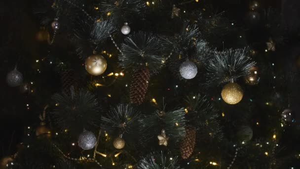 In der Nähe leuchtet ein Weihnachtsbaum, der nachts glitzert. Neujahrstanne mit Dekoration und Beleuchtung. Weihnachtsbaumschmuck Hintergrund. Viele große goldene Kugeln an Tannenbaum Neujahr und Weihnachten. — Stockvideo