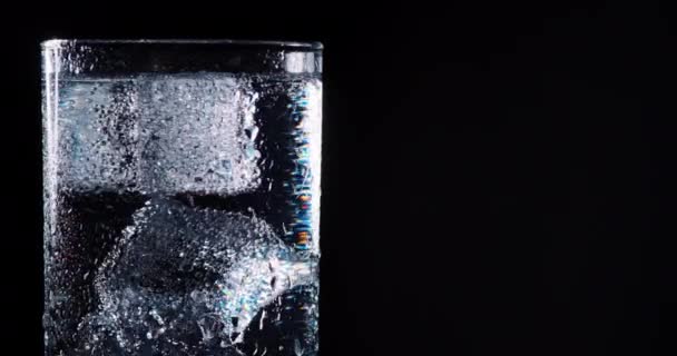 Closeup pouring clean fresh Water in a Glass with splash and bubbles, isolated on Black background. Ice, bubbles and splash. Cold tonic Mineral water. Healthy lifestyle. Living water. Drinking water. — Stock Video