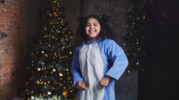 Rolig afrikansk söt liten flicka dansar och firar jul vinter semester i dekorerat vardagsrum. Aktivt nöje med barn, Nyårsevenemang. — Stockvideo
