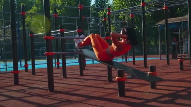 Menina atlética em roupas esportivas bombeando abdominais em pista de corrida em campo de esportes. — Vídeo de Stock