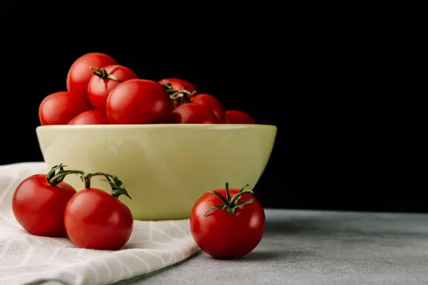 Koyu arkaplanda yaprakları olan kırmızı domatesler.