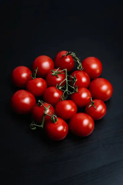 Koyu arkaplanda yeşil yapraklı bir grup kırmızı domates.