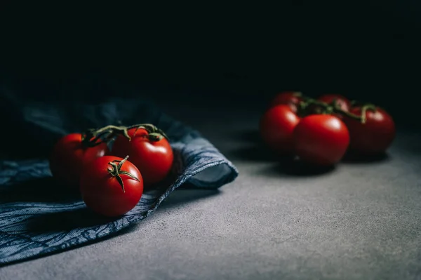 Koyu arkaplanda yeşil yapraklı kırmızı domatesler