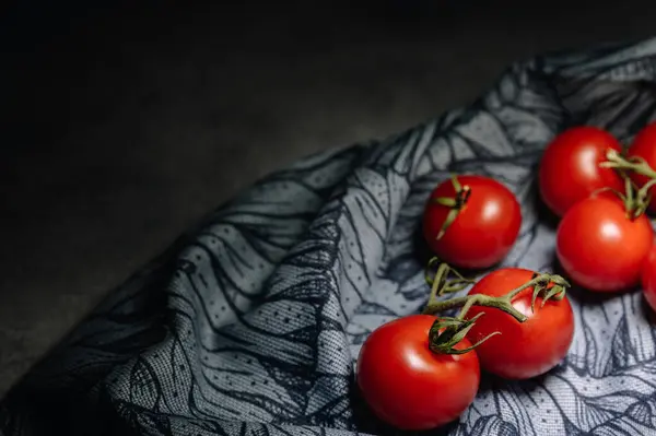 Gri arkaplanda yeşil yapraklı kırmızı domatesler.