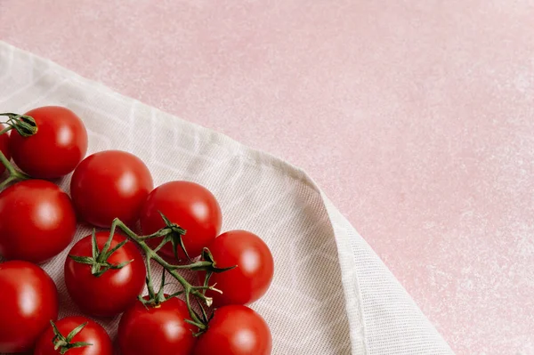 Pembe arka planda yeşil yapraklı kırmızı domatesler.