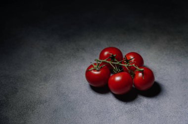 Gri arka planda yeşil yapraklı bir avuç kırmızı domates. Organik sağlıklı yiyecekler. Çiğ domates. Taze sebze.