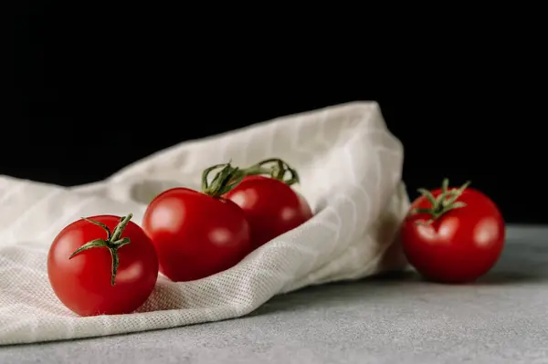 Gri arka planda yeşil yapraklı kırmızı domatesler. Organik sağlıklı yiyecekler. Çiğ domates. Taze sebze.