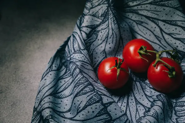 Gri arka planda yeşil yapraklı kırmızı domatesler. Organik sağlıklı yiyecekler. Çiğ domates. Taze sebze.