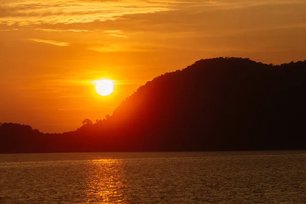 Tayland adasında altın saat gün batımı. Siyah kayaların üzerinde sersemletici güneş