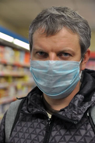 Portrait of a young man with a medical mask in a supermarket. COVID-19