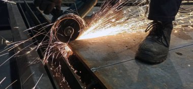 Fabrikadaki işçiler metali kesiyor. kıvılcımlar uçuşuyor