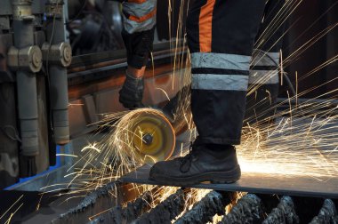 Fabrikadaki işçiler metali kesiyor. kıvılcımlar uçuşuyor