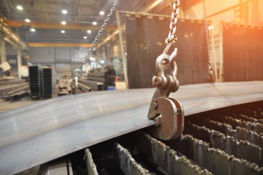 Metal levha yüklemek için zincir ve kanca kaldırıyorum. Kesmek için bir plazma kesme makinesine metal yerleştiriliyor.