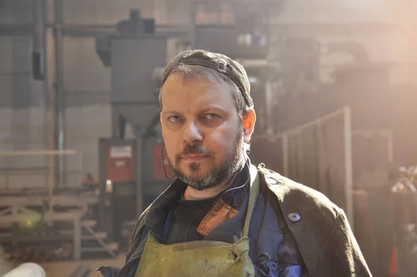 Fabrikada yapım odasında iş tulumu giymiş sakallı bir işçi. Yakın plan.. — Stok fotoğraf