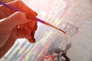 Sayılarla boyamak. El bir fırça tutar ve boyar. Hobi