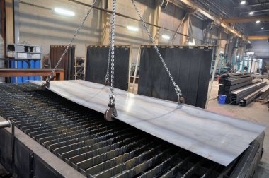 Metal levha yüklemek için zincir ve kanca kaldırıyorum. Kesmek için bir plazma kesme makinesine metal yerleştiriliyor.