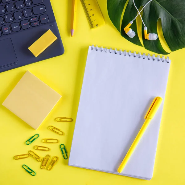 mockup of learning or business process. Blank notebook, pen, laptop, sticky paper sheets, ruler, pencil and palm monstera leaf on bright yellow background. Flat lay top view, copy space. Square