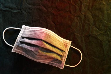 Tıbbi maske ya da siyah kağıt arka planda kırmızı-sarı ışık ile cerrahi kulak ilmeği maskesi                               