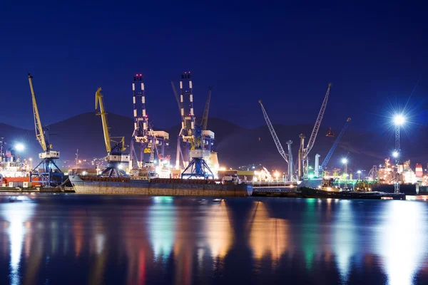 Porto de carga iluminado em Novorossiysk à noite com terminais de contentores, navios de carga e guindastes . — Fotografia de Stock