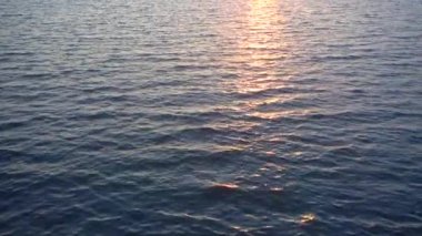 Güzel su yüzeyi ve ufukta güneş. Döngülü tam hd video.