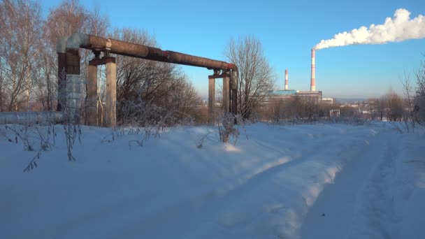 Ipari táj. Az erőmű vízvezetékei és kéménye télen. — Stock videók