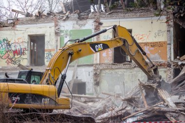 Obninsk, Rusya - Şubat 2020: Kazı kovası kullanılarak eski bir tuğla binanın yıkılması. SSCB mimarisi