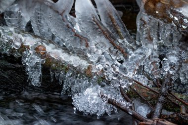 Kışın nehirde çok güzel buz birikiyor. Güçlü buz sarkıtları ve buzlar donarken suyun yanında.