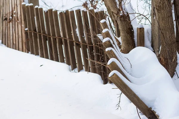 Fallen wooden fence covered with snow in winter