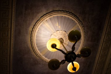 Tavanda eski bir avize, klasik bir şekilde alçı döşemeli.