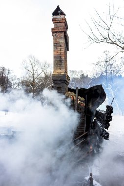 Yangından sonra kalan bir ev. Sobanın tuğla tüpü yoğun dumanla kaplıdır. Kasvetli külün dikey görünümü