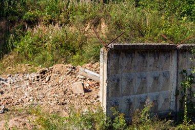 Yıkılmış bir binanın kalıntıları ve Rusya 'nın SSCB zamanından kalma askeri bir birliğin topraklarında dikenli tellerle çevrili kırık bir çit.