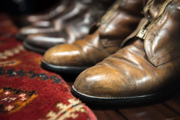 Botas de cuero gastado y alfombra — Foto de Stock