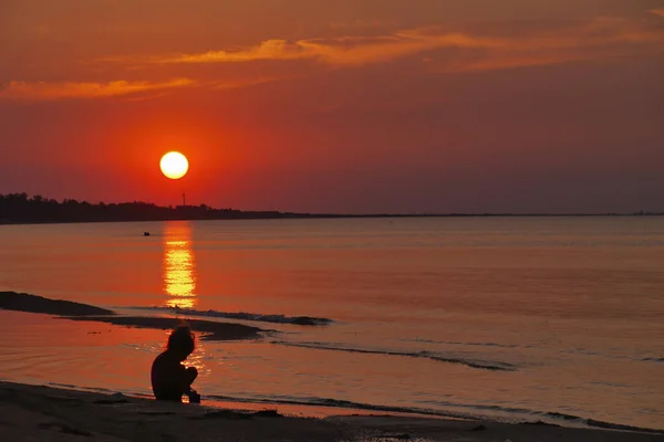 Silhouette of a little girl at sunset by the sea — Stock Photo, Image