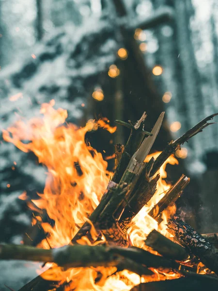 Detailní záběr táborového ohně v lese s přístřeší pro přežití s vánoční věnce v pozadí — Stock fotografie