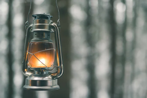 Lâmpada de querosene com luz no fundo turvo da floresta de inverno — Fotografia de Stock