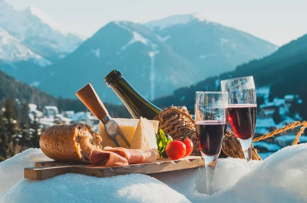 Traditionell italiensk mat och dryck utomhus under solig vinterdag. Romantisk alpin picknick i Dolomiter med berg bakgrund, Lambrusco ost baguette och skinka på snö. — Stockfoto