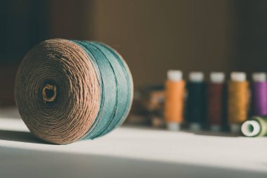 Masanın üzerinde bej renkli iplik yumağı ve arka planda renk karmaşası. Cesur zemin modayı rengi