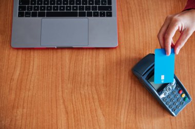 Kadının eli, erişimi olmayan cihazda kredi kartıyla ödeme yapıyor.