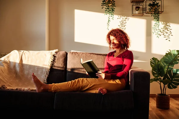 Žena čtení knihy na gauči během karantény pro coronavirus - pobyt doma koncept — Stock fotografie