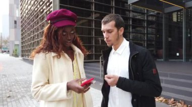 İş arkadaşları iş yerlerinin dışında cep telefonlarıyla işlerinden bahsediyorlar.