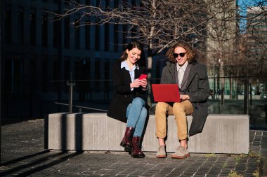 Dışarıda dizüstü bilgisayar ve telefon kullanan iş adamları.