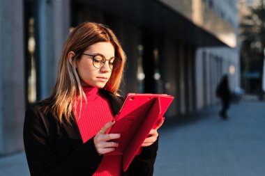 Dışarıda dikilirken dijital tablet kullanan bir kadın.