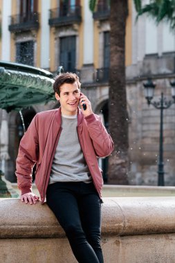 Genç adam dışarıda telefonla konuşuyor..