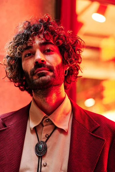 Genç beyaz adam mavi ve kırmızı ışıkları olan neon ışığa yakın.