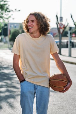 Elinde basketbol topu olan genç bir adam.