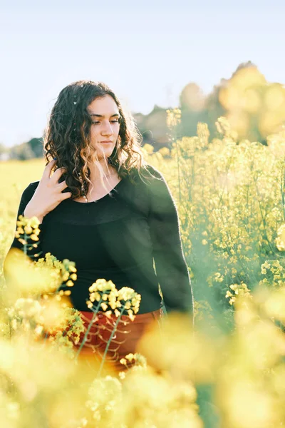 Jeune femme courbée dans un champ pétrolifère de colza au printemps entouré de fleurs jaunes — Photo